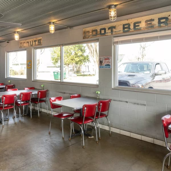 Interior of Barnett's Dairyette with red chairs, gray tables, and large windows showing a drive-thru.